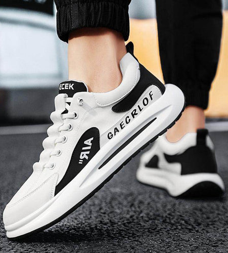 White sneakers with black accents worn by a person on a blurred background