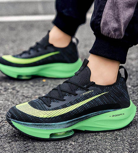 Black and green running shoes on a person's feet on a street.