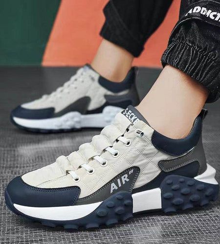 Sneakers with a mix of white, navy, and gray colors on a textured surface.