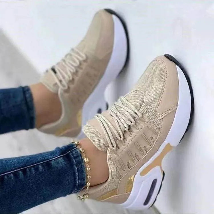Beige sneakers with white soles worn by a person on a light background