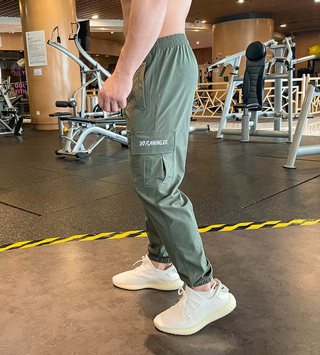 Person wearing green cargo pants and white sneakers in a gym setting