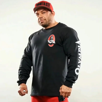 Man wearing a black long-sleeve shirt with a logo and red pants against a white background