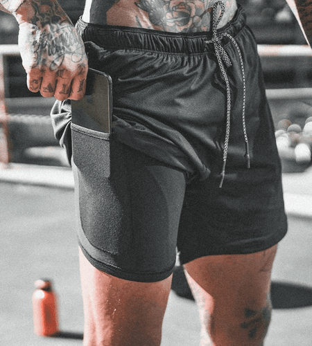 Person wearing black athletic shorts with a pocket on a blurred background