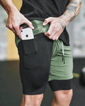 Person wearing black and green athletic shorts with a phone in a pocket.