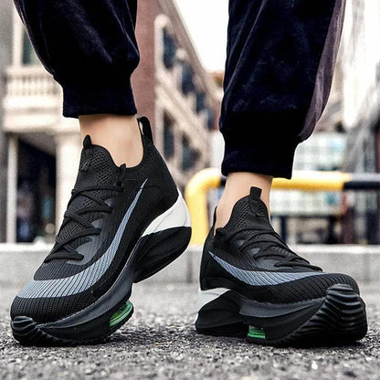 Black athletic shoes with green accents worn on a blurred street background