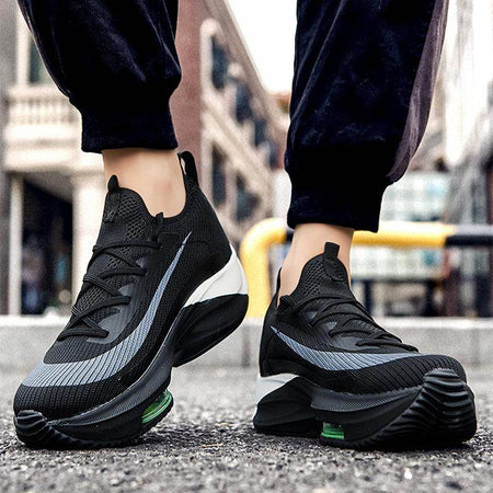 Black athletic shoes with green accents worn on a blurred street background