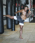 Man practicing martial arts in a gym with punching bags in the background