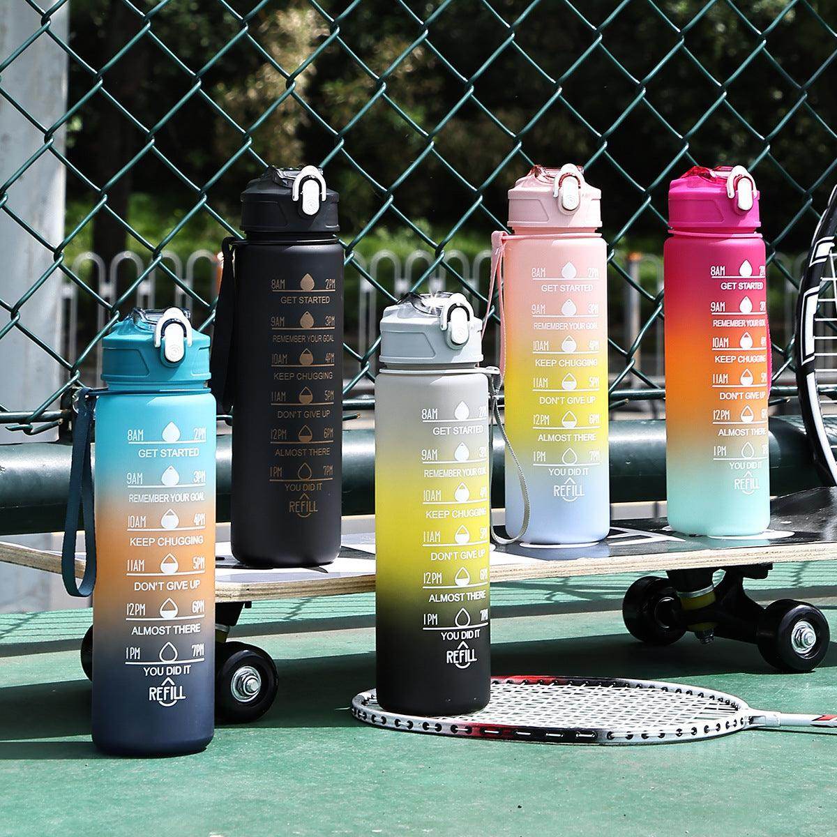 Set of colorful water bottles with gradient designs on a sports court.