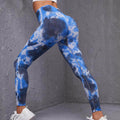 Blue tie-dye leggings worn by a person against a gray wall.