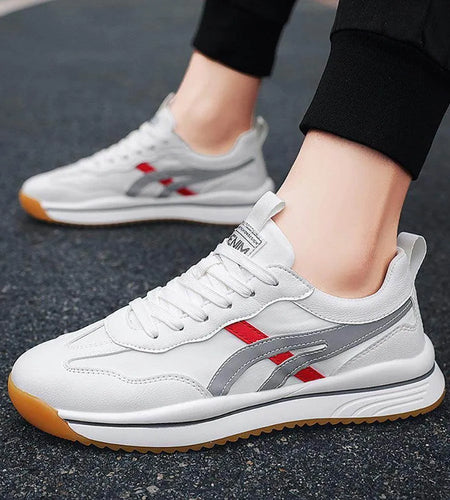 White sneakers with red and gray accents worn on a dark surface