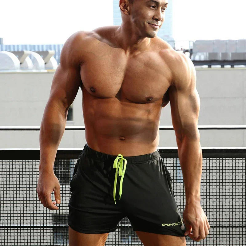 Muscular man wearing black shorts with a neon green drawstring on a rooftop background.