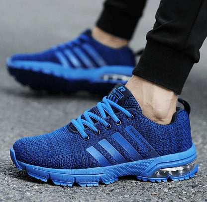 Blue athletic shoes with a brand logo worn by a person on a gray surface