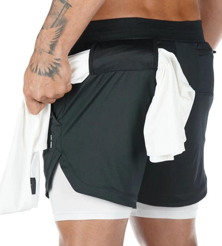 Person wearing black athletic shorts with white inner lining on a white background