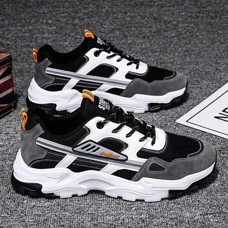 Pair of black, gray, and white sneakers on a dark textured surface.