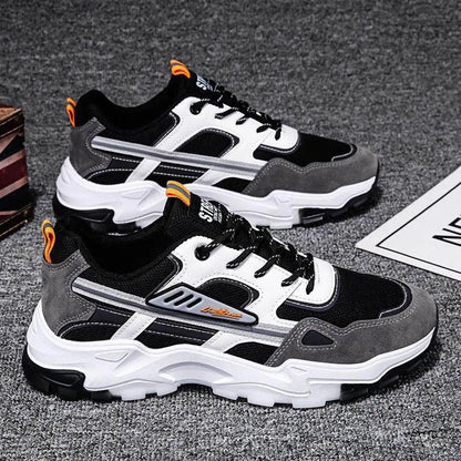 Pair of black, gray, and white sneakers on a dark textured surface.