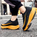 Black and yellow sneakers on a person walking on a street.