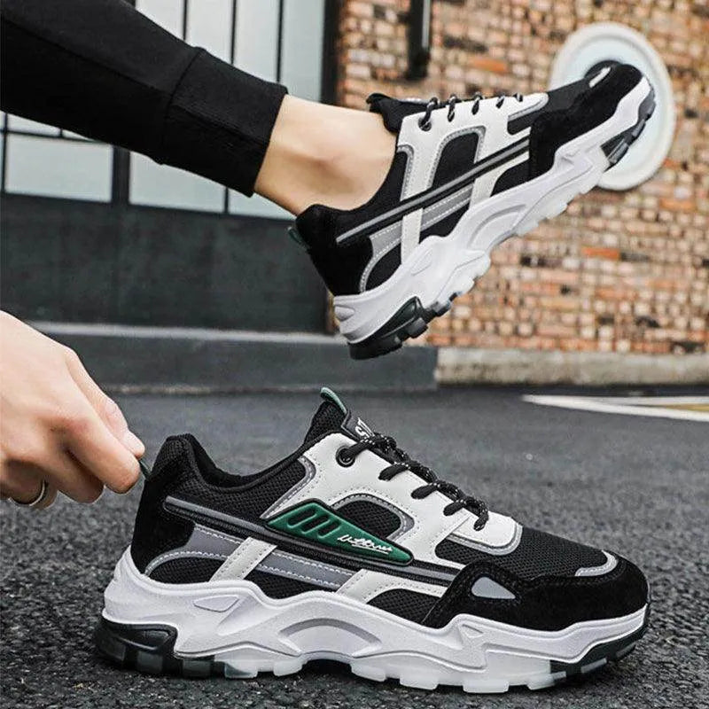 Black and white sneakers with green accents worn by a person on a street.