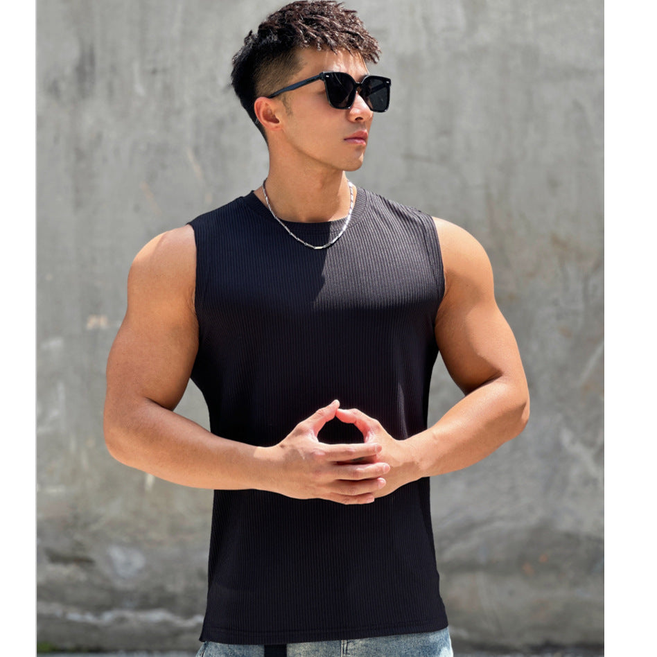 Man wearing a black sleeveless shirt and sunglasses against a gray wall