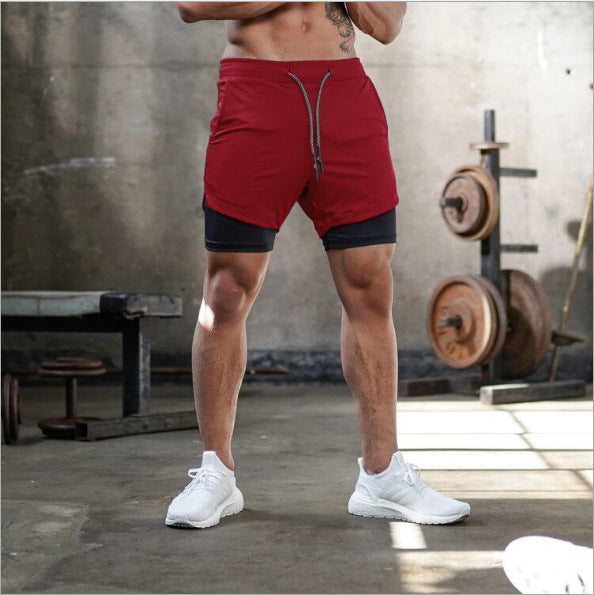 Person wearing red athletic shorts with a black inner layer in a gym setting