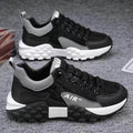 Black and gray sneakers with white soles on a textured surface