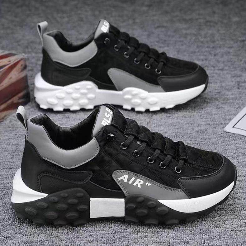 Black and gray sneakers with white soles on a textured surface