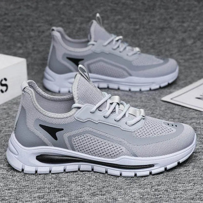 Gray running shoes with white soles on a gray surface