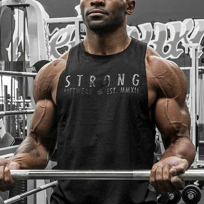 Muscular man lifting weights in a gym wearing a black tank top with 'STRONG' printed on it.