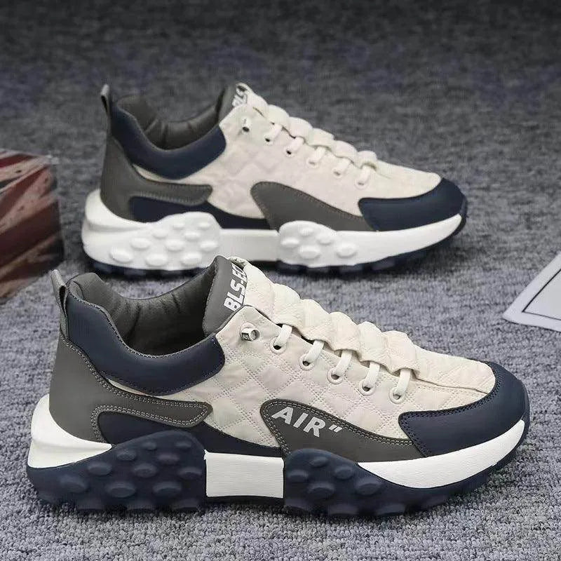 Pair of gray and navy sneakers on a textured surface