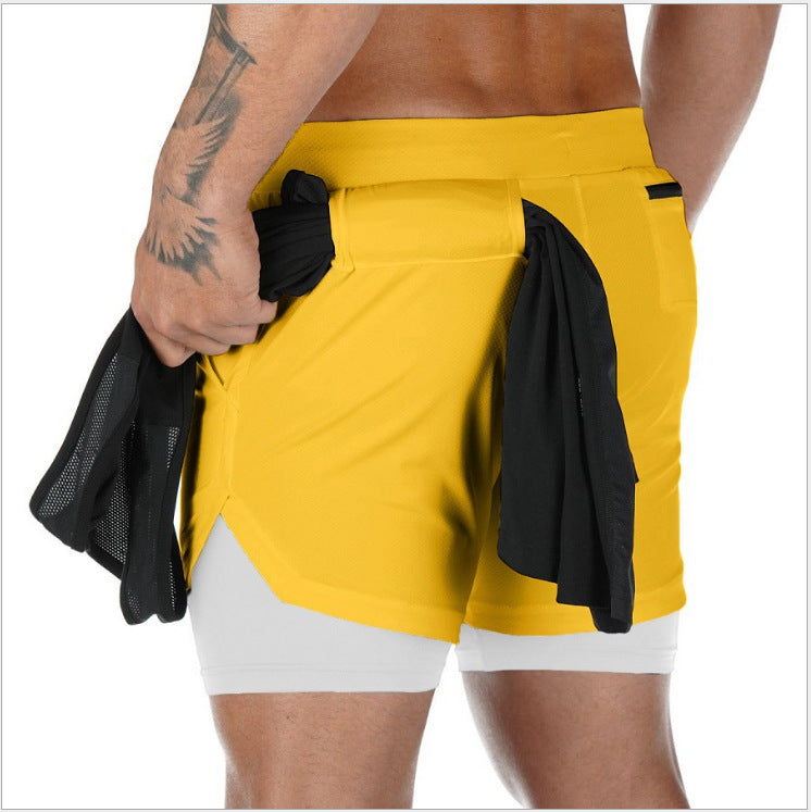Person wearing yellow athletic shorts with a black towel over the shoulder on a white background