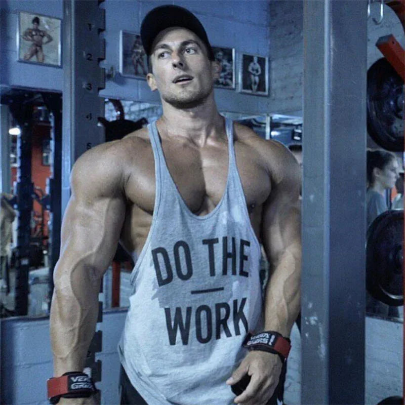 Muscular man in a gym wearing a tank top with 'Do The Work' text