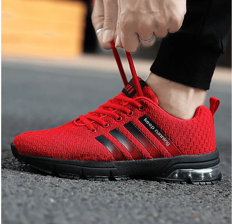 Red athletic shoe with black stripes being worn on a blurred outdoor background