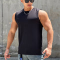 Man wearing a black sleeveless shirt and sunglasses against a gray wall.