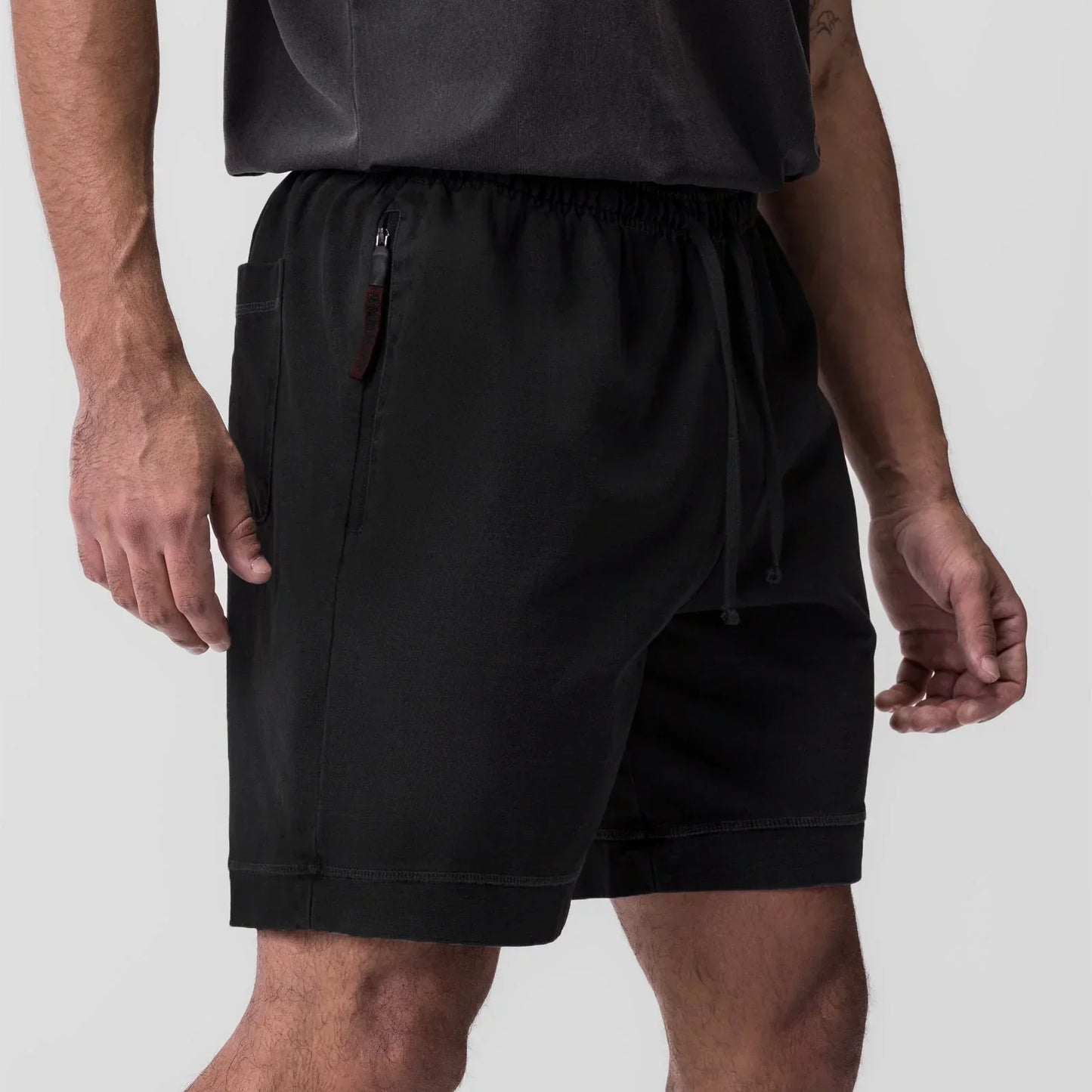Person wearing black shorts on a plain background