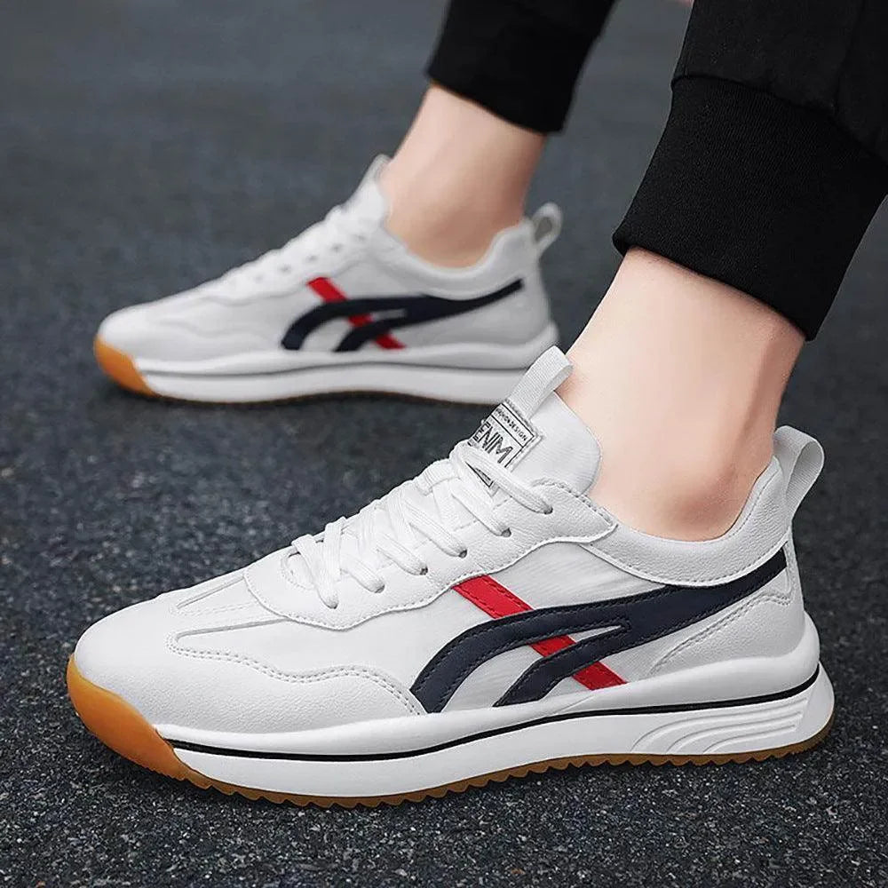 White sneakers with red and blue accents worn by a person on a dark surface
