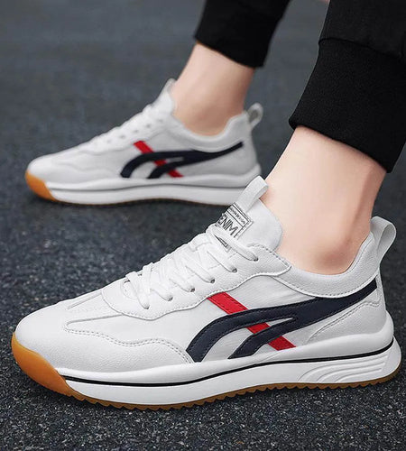 White sneakers with red and blue accents worn by a person on a dark surface