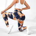 Person wearing tie-dye leggings with blue and orange patterns on a white background