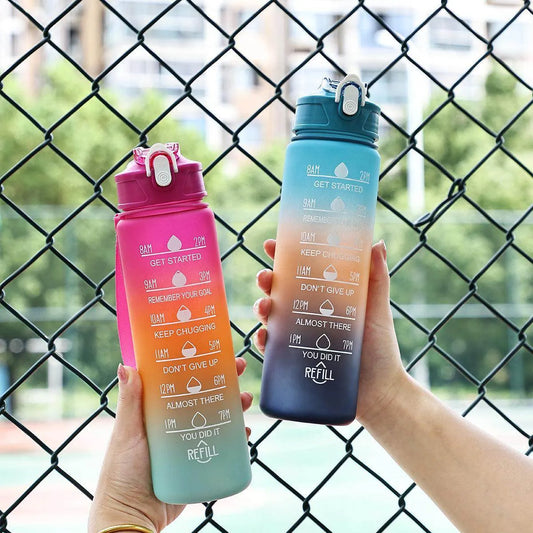 Two motivational water bottles held by hands against a chain-link fence.