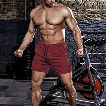 Muscular man in maroon shorts standing in a gym setting