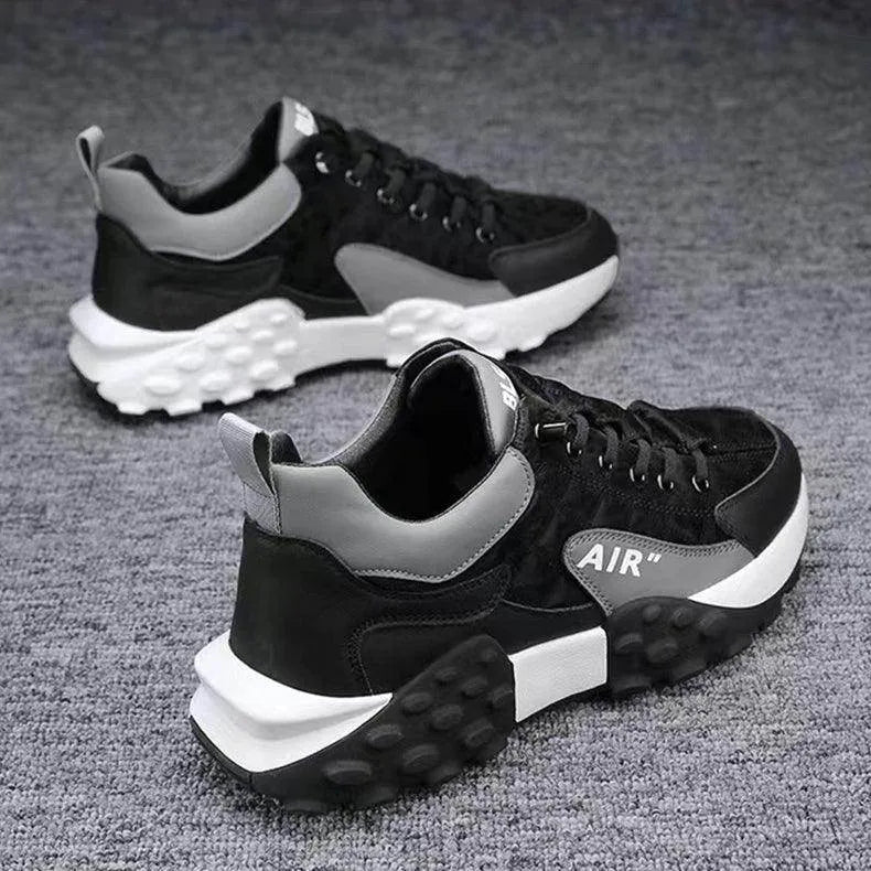 Black and gray sneakers with white soles on a gray surface