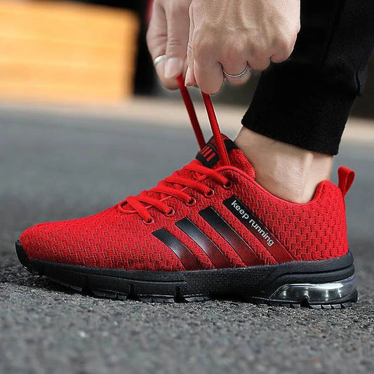 Red running shoe with black stripes being worn on a blurred background