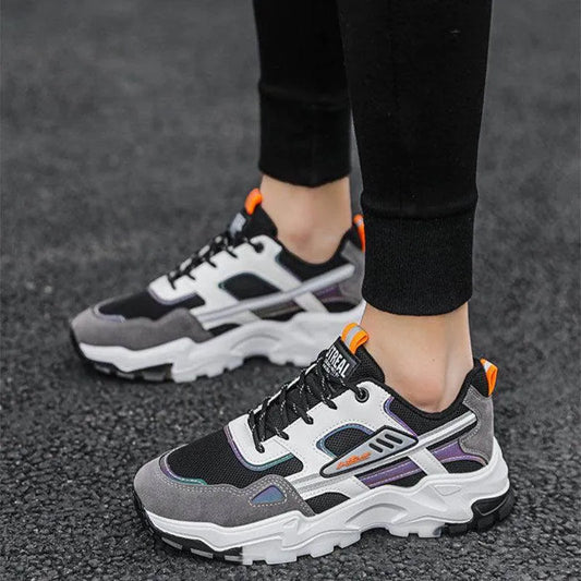 Person wearing black and gray sneakers with orange accents on a dark surface