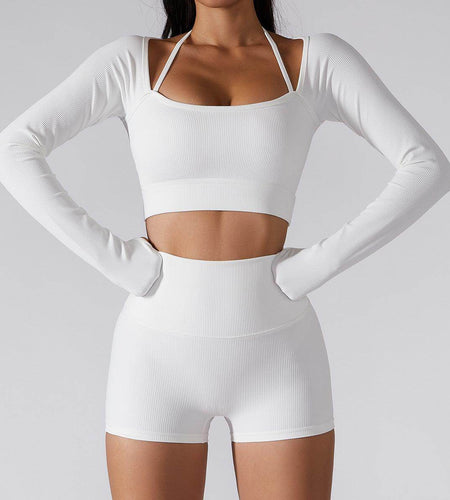 Person wearing a white long-sleeve crop top and shorts set on a light gray background