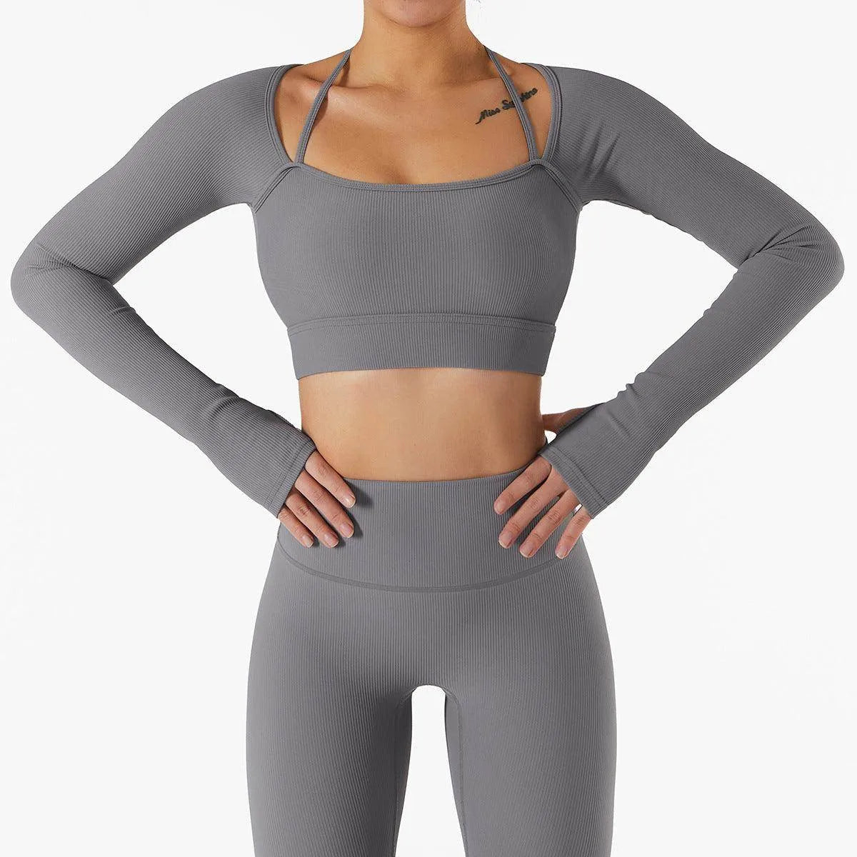 Person wearing a gray long-sleeve athletic top and leggings on a white background