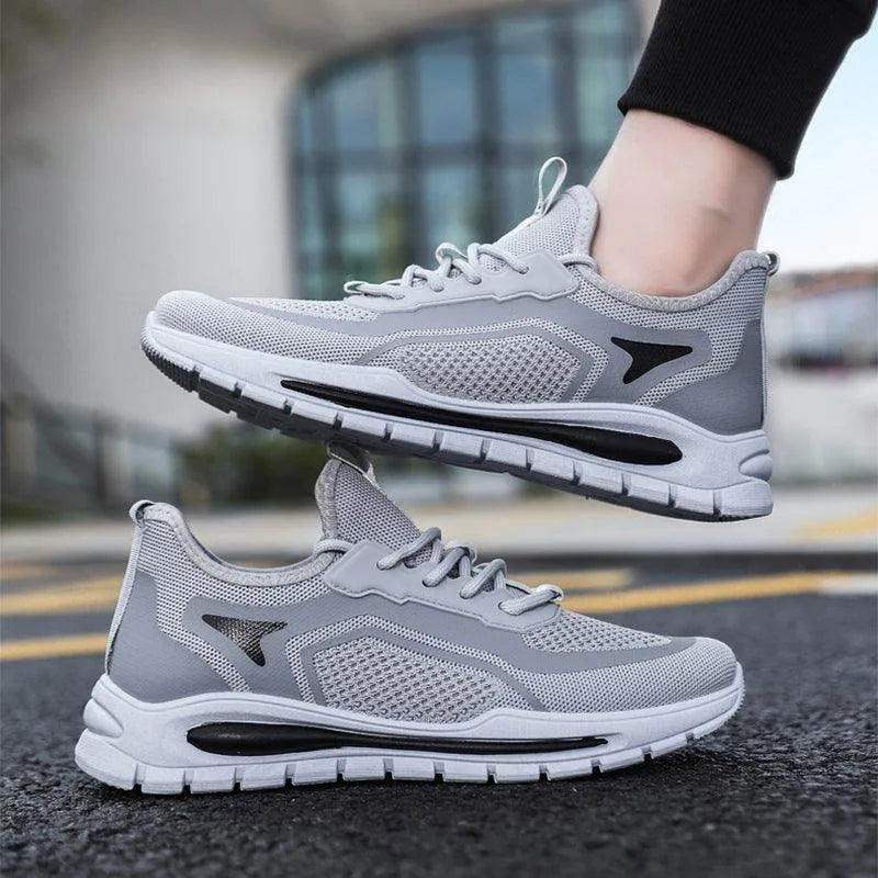Gray athletic shoes with black accents worn by a person on a blurred street background