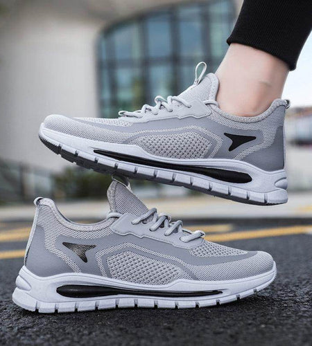 Gray athletic shoes with black accents worn by a person on a blurred street background