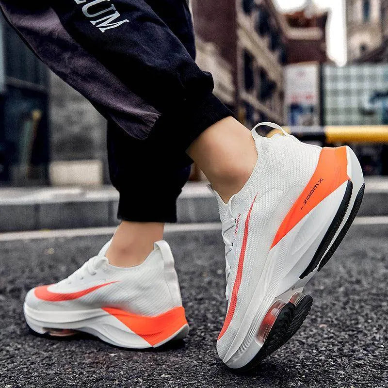 White sneakers with orange accents worn on a street.