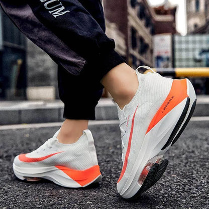 White sneakers with orange accents worn on a street.