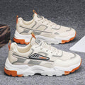 Pair of beige sneakers with orange accents on a gray surface