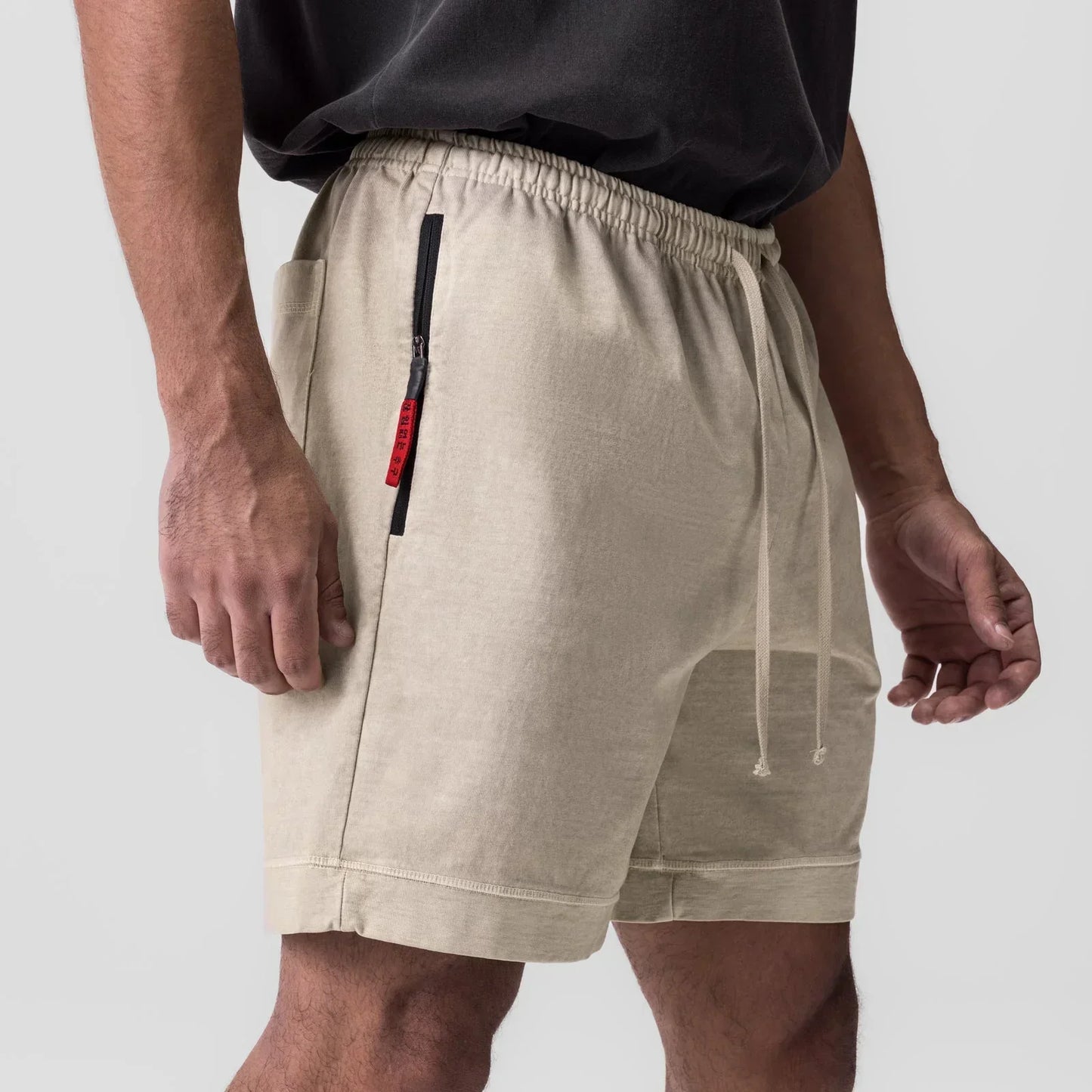 Beige shorts with a red zipper on a plain background
