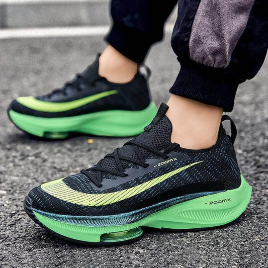 Black and green running shoes on a person's feet on a street.
